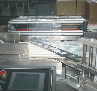 Gift box blanks are conveyed into centerfolded film formed into a tube by this angled inverting head.