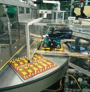 A customized pick-and-place arm places markers into blister cavities on the rotary table of an eight-station heat-sealing machin