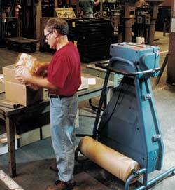 A customer service employee at Mathews uses the PadPak Jr. to prepare spare parts for shipment.