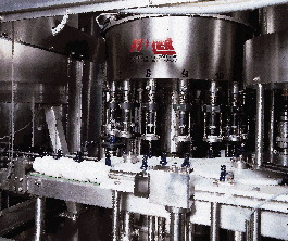 At the machine1s infeed, bottles are first handed off to the 16-valve fill-to-level filler (above). Platforms elevate each bott