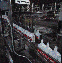 This photo, taken when Amsoil used prelabeled bottles, shows a group of 16 quart bottles getting filled simultaneously by a pos
