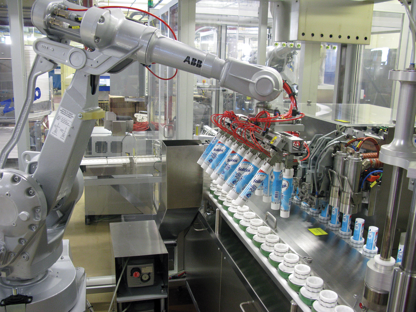 Empty tubes are picked from boxes by the robot&rsquo;s twin-row end effector and placed in the filler&rsquo;s pucks.