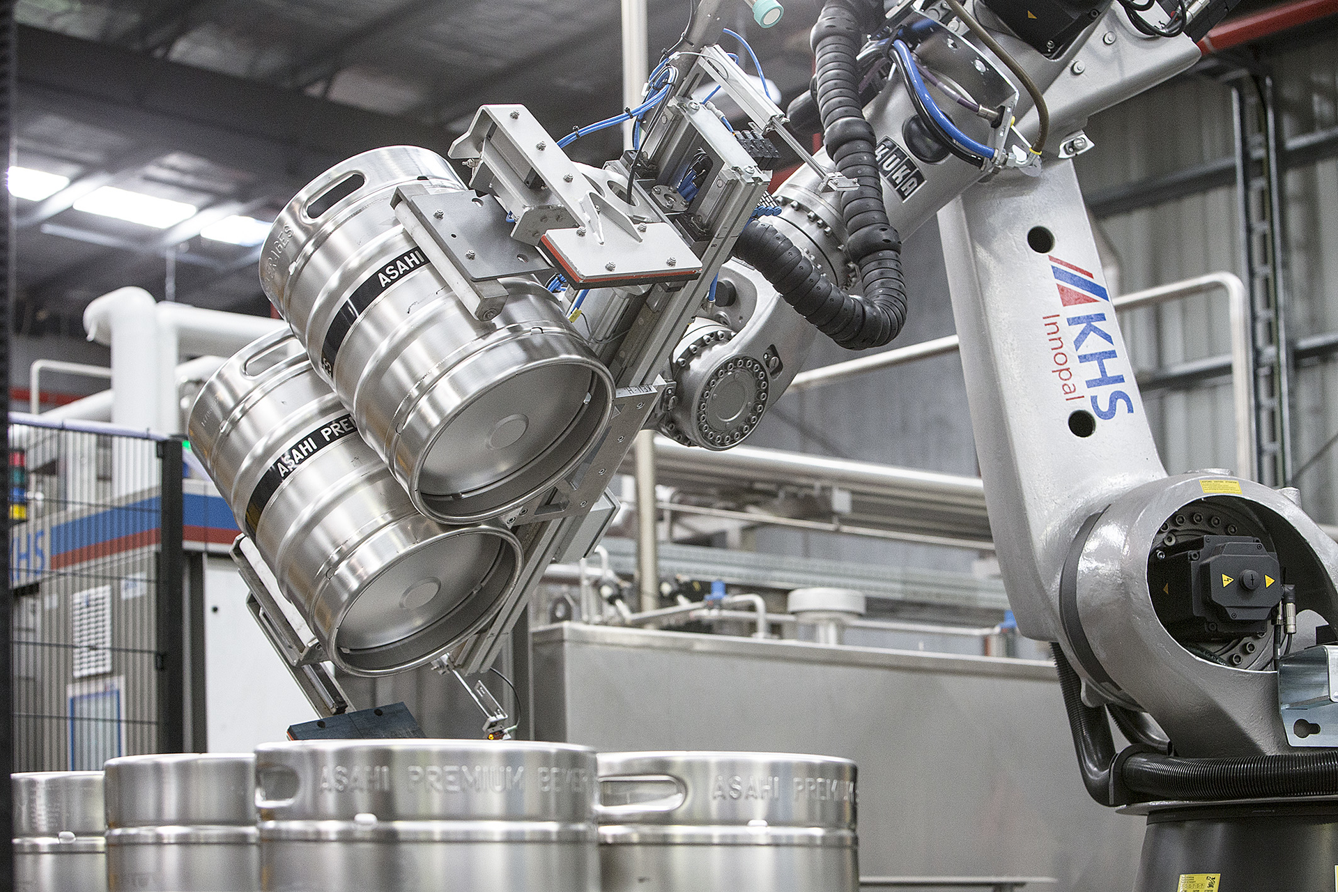 Kegs are turned by the robot and placed on a conveyor leading to the keg washer.