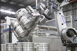 Kegs are turned by the robot and placed on a conveyor leading to the keg washer.