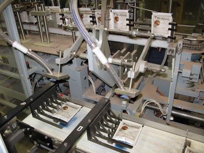Once pouches are cut into individual units, a pick-and-place device puts each pouch on a pedestal checkweigher.