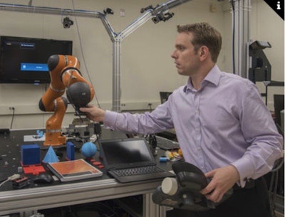 NIST engineer Jeremy Marvel adjusts a robotic arm used to study human-robot interactions. Photo courtesy of F. Webber/ NIST.