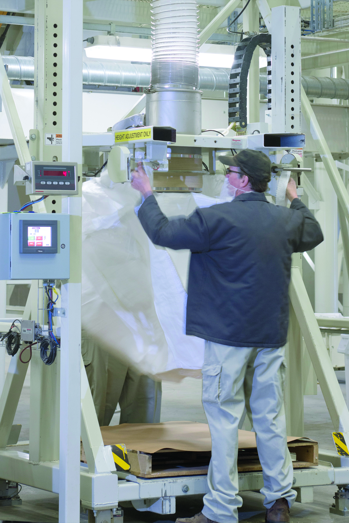 Operator attaches bag loops to retractable bag hooks that suspend the bag during filling. Photo courtesy of Flexicon.