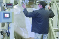 Operator attaches bag loops to retractable bag hooks that suspend the bag during filling. Photo courtesy of Flexicon.