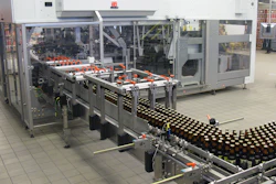 Shortly after freshly filled bottles enter the Varioline packing system, they’re picked and placed into cases that have six-pack paperboard carriers already in them.