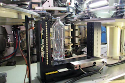 The Process Pilot goalpost sits in the blowmolder takeout area, its sensors measuring bottle thickness at 12.5-mm intervals along the sidewall.