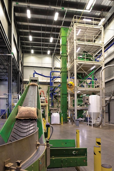 Burlap sacks travel to the automatic bag slitting machine, which places green coffee beans in the hopper and then disposes the sack. This limits handling of the product, reducing worker and food safety risks. Photo by Brian Hippensteel/Brand Neue.