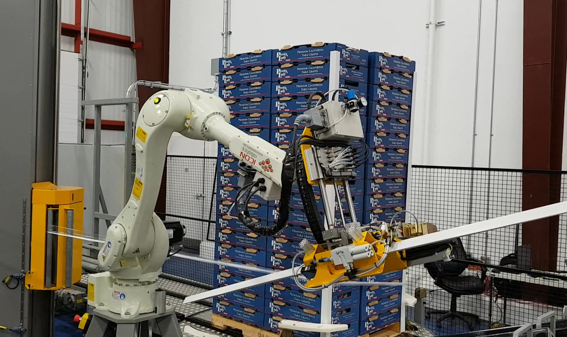 A six-axis articulated robot applies corner boards to the four edges of the pallet, after which it is stretch wrapped.