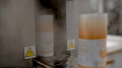 Bottles with applied shrink sleeves enter a steam tunnel to shrink labels around the bottles.