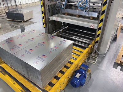 Sheets of decorated tinplate are pulled into a machine that slits them into six before welding each piece into a can body.