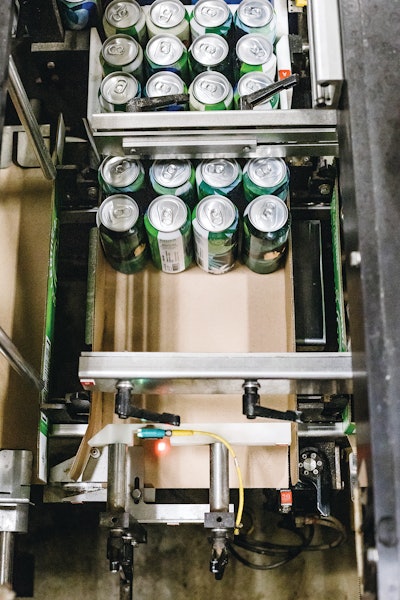 A corrugated tray is formed around a 6 x 4 format of shrink sleeved cans at Collective Arts Brewing.
