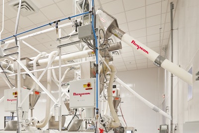 Flexible screw conveyors transfer ingredients from bulk bag dischargers, through a wall, to feed packaging machines in the next room. The screws prevent product contact with seals or bearings.