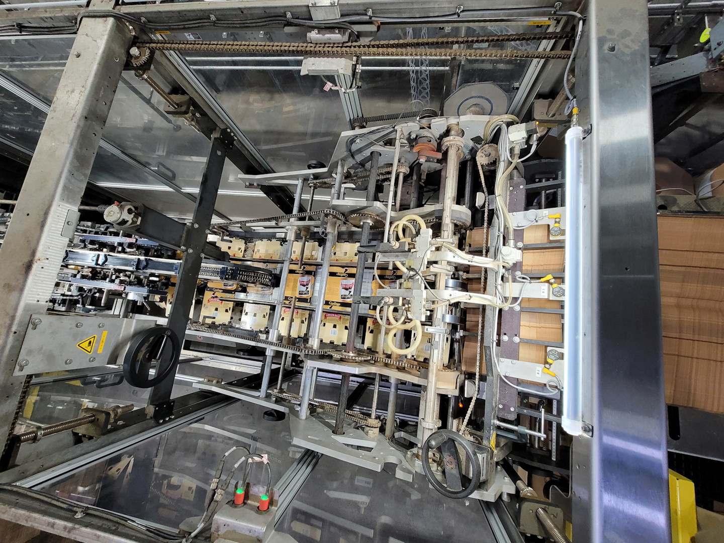 An overhead view and a side view illustrate how printed paperboard cartons are indexed out to cover, then enclose the two parallel lanes at a depth of three cans, creating the 2x3 six-pack format. No glue is required in the operation.