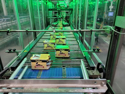 An integrated turner/divider turns the six packs to a wider profile with three cans leading and three cans trailing, then bifurcates them into two lanes. This slows the line speed for tray-forming and palletizing operations without changing throughput.