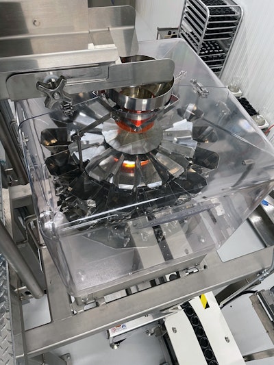 On a mezzanine, a product infeed conveyor introduces cannabis flower to a multihead combination scale.