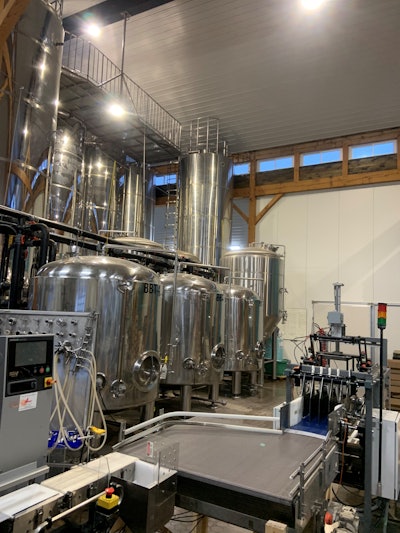 Accumulation table of MacKinnon tray packer and some of its vessels. The brew system makes 25 hl batches and the company has tanks of 50, 150, and 200 hl.