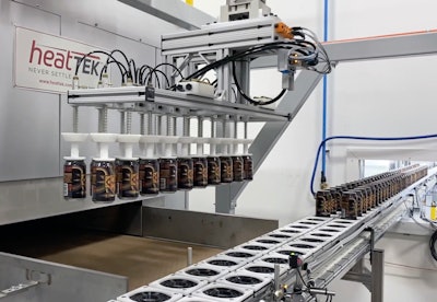 A two-axis gantry robot uses vacuum pickup to pick 20 cans and place them on the infeed belt of an oven that cures the varnish.