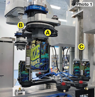 Cans exit the printing module by way of a SCARA robot equipped with customized end effectors (A and B) that place cans two at a time on a rotating transfer wheel. Another robot has end-of-arm tooling (C) that picks two cans at a time from the transfer wheel by plunging to the interior can bottoms so that vacuum pickup cups can affix themselves to the can bottoms.