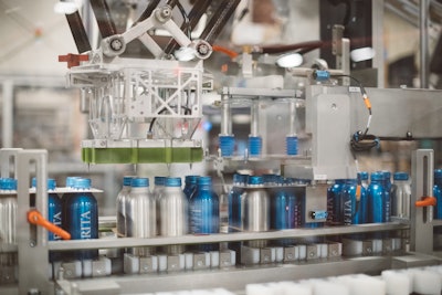 A custom, Sherpa-engineered applicator applies a Fishbone carrier to the top of a six-pack of bottles.