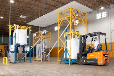 The flexible screw conveyor at left transfers roasted coffee beans from the bulk bag discharger to the grinder, while the conveyor at right moves ground coffee to the bulk bag filler.