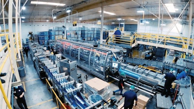 Infeed of 5-oz and 7-oz canned and glue-applied labeled product into the cartoner at the Santa Fe, Calif. Bumble Bee facility. Note the layout of three parallel tracks, with product first entering the space and feeding the cartoner on the center track. After product is cartoned and laned, it turns sharply 180 deg, carrying product downstream while parallel to the cartoner. Product then takes another, wider 180-deg turn around the cartoner, and finally travels parallel to the previous two tracks again for tray packing.