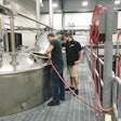 Lead Distiller Andrew Holt and Distiller Matthew Sauer oversee the mash process on one of the four fermenters used to make moonshine.