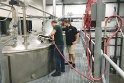 Lead Distiller Andrew Holt and Distiller Matthew Sauer oversee the mash process on one of the four fermenters used to make moonshine.