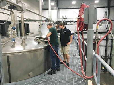Lead Distiller Andrew Holt and Distiller Matthew Sauer oversee the mash process on one of the four fermenters used to make moonshine.