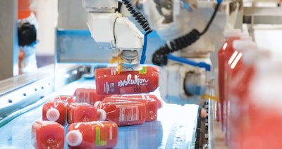 Pick-and-place robots line bottles up to ready them for packaging.