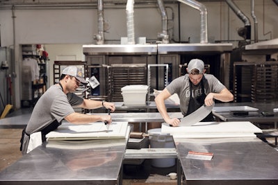 Workers cut ReGrained upcycled snack bar prototypes for a brand partner.