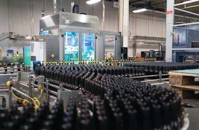Bottling operations begin with a Uni-Pak floor-level depallitizer (left). Mass flow bottles are then single filed for filling and labeling and filling, after which finished bottles are conveyed to case-packing operations (center background).