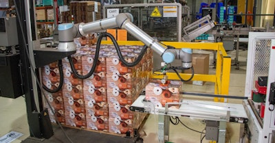 One of Napco’s two Robotiq cobot palletizers picks a sealed carton of coffee capsules from a conveyor for placement on a pallet.