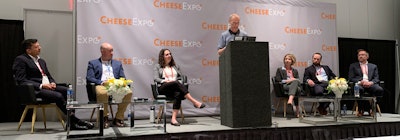 Panelists (from left) Sumeet Mathur, Josh Luth, Shaina Ashare, Michel Wattiaux (standing), Erica McDougall, Shane Reynolds, and Kyle Jensen discuss sustainability in the dairy industry during a discussion at CheeseExpo.