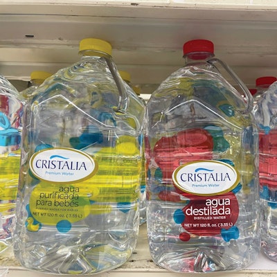Multiple varieties of Cristalia water on a retail shelf. While a gallon is equivalent to 128 oz, 120-oz jugs (near gallon equivalent) are the standard in Puerto Rico.