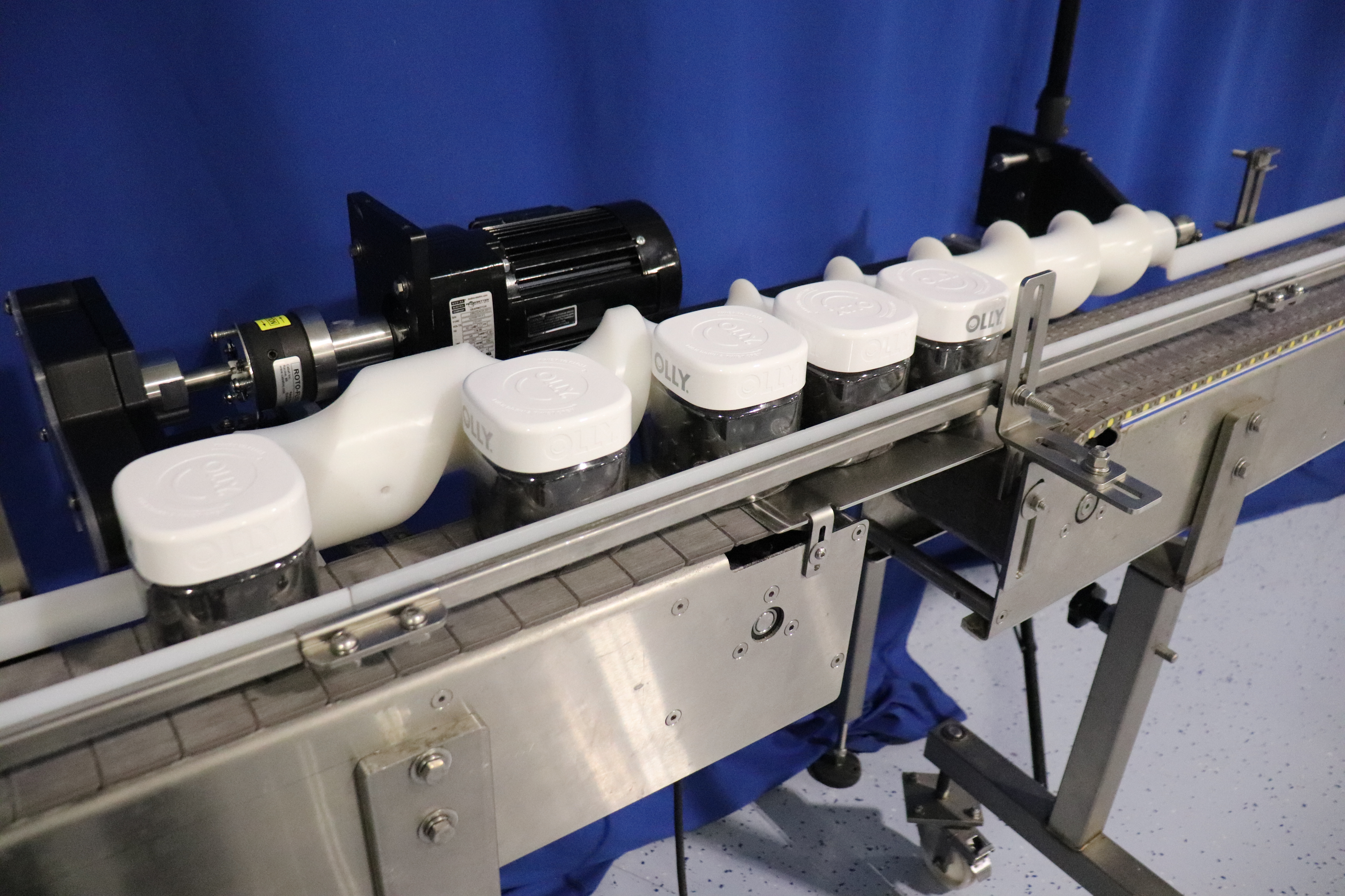 A timing screw squares Olly containers over the date coder before releasing them down the conveyor 8.25 inches apart.