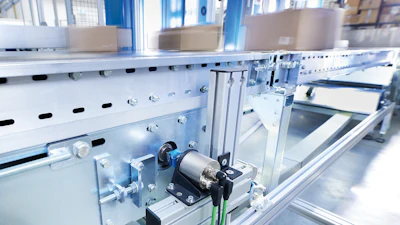 Automated packaging conveyor with cardboard boxes in manufacturing facility
