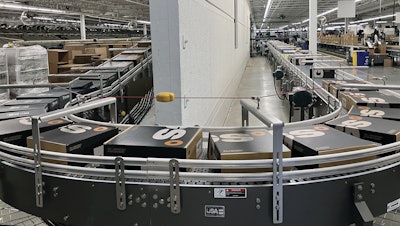 Boxes of footwear are conveyed on friction-top belting down a controlled 30’ decline before entering a 180-deg curve that uses side-flexing chain to stabilize boxes during the turning process.