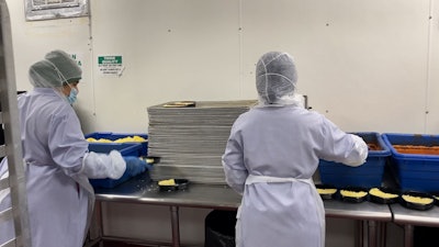 Manually portioning meals into two-compartment trays limited throughput to around 10–15 trays per minute per line.