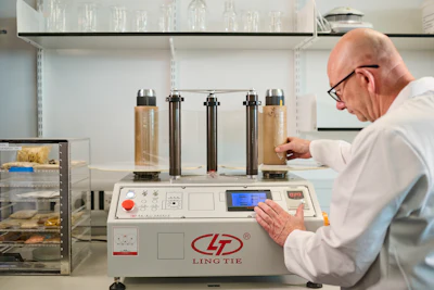 Laboratory technician operating Ling Tie testing equipment with cylindrical sample containers
