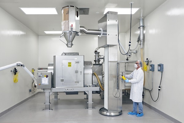 Drums containing each ingredient are lifted, aligned with the mixer's stationary inlet, and emptied—in a prescribed order according to the Master Batch Record.