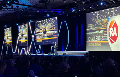 RA Challenges conference stage with large screens and presentation backdrop