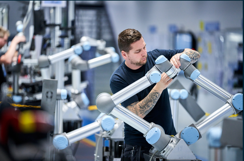 Technician working with collaborative robotic arms in high-tech manufacturing facility
