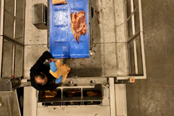 A worker loads pork bellies into the slicer.