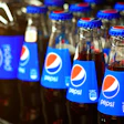 Multiple Pepsi glass bottles lined up with blue labels and red-white logos