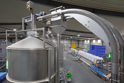 In the foreground, a Flexi-Disc System feeds a storage silo, while in the background, filled bulk bags of whole blanched almonds are prepared for shipment to Almondco’s consumer product processors.