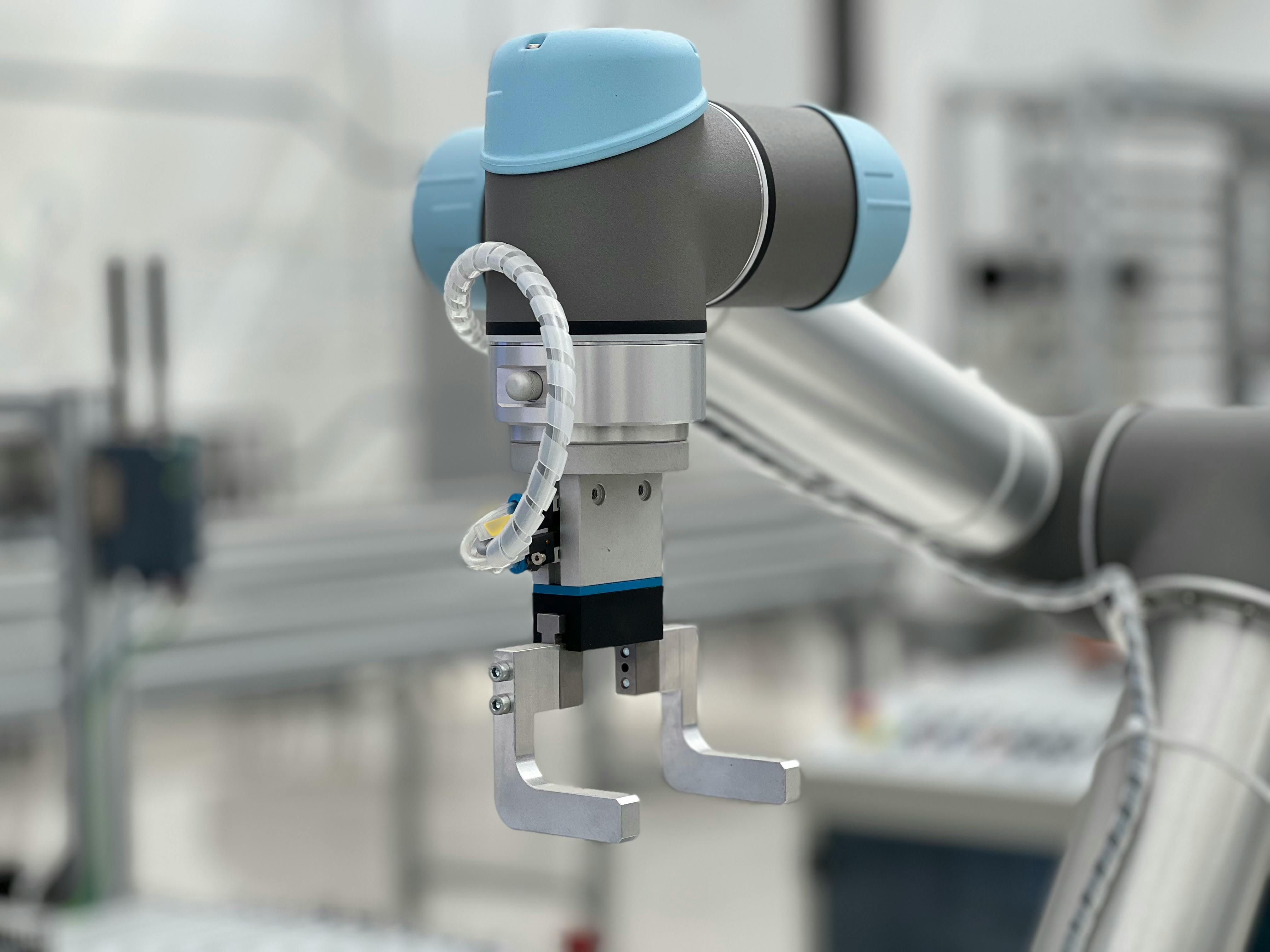 Blue and gray gimbal camera stabilizer mounted on robotic arm in industrial setting